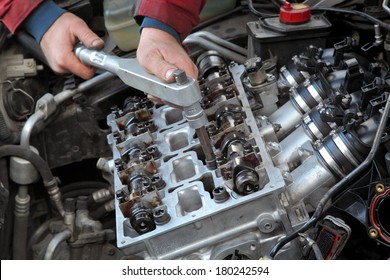 Mechanic fixing cylinder head with camshaft of car engine with socket wrench