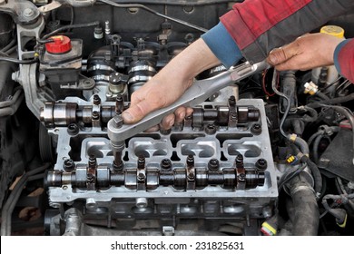 Mechanic fixing cylinder head with two camshaft of car engine with socket wrench