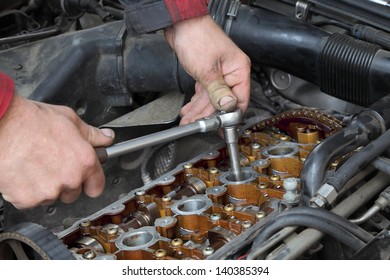 Mechanic Fixing Spark Plug To Open Car Engine With Ratchet, Visible Camshafts,  Pulley, Belt, Timing Chain