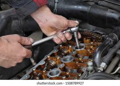 Mechanic Fixing Spark Plug To Open Car Engine With Ratchet, Visible Camshafts,  Pulley, Belt, Timing Chain