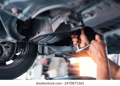 A mechanic in a garage repairs a car engine, oil-stained hands working with tools - Powered by Shutterstock