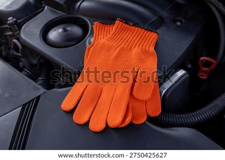 Mechanic gloves are placed on the engine as a worker takes a break from fixing the car on a weekday.