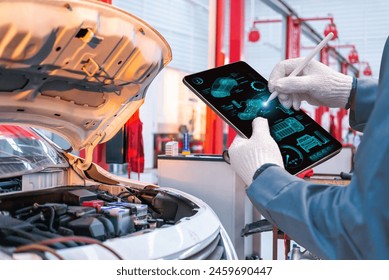 A mechanic in gloves uses a high-tech digital tablet to perform advanced diagnostics on a car engine in a workshop. - Powered by Shutterstock