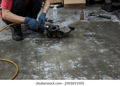 A mechanic grinding an exhaust manifold on his dirty greasy garage floor - Powered by Shutterstock