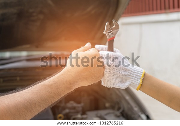 Mechanic hand checking and fixing\
a broken car in  garage.hand of mechanic with thumbs up and\
tool
