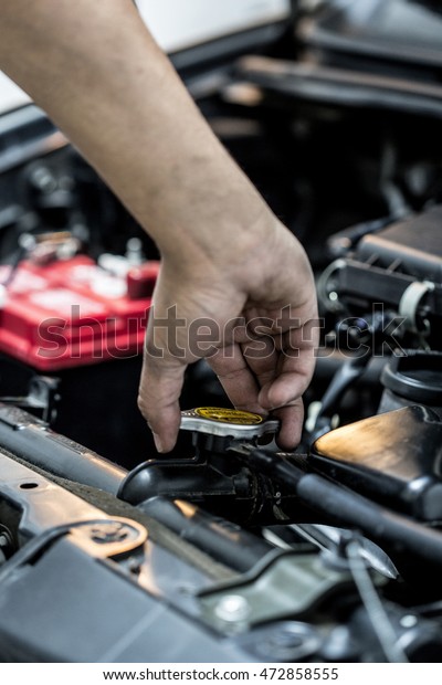 Mechanic hand checking and fixing a broken car in\
car service garage