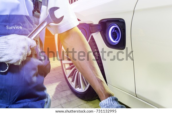 Mechanic hand holding the wrench on Electric\
car background. The concept of repairing electric car is a\
technology in the\
future.\
