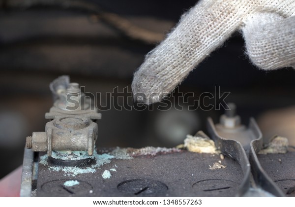 Mechanic hand\
pointing car battery in garage .\
Old battery corrosion deteriorate\
leaking with blue acid powder.\
Battery terminals corrode dirty\
damaged problem\
checking.