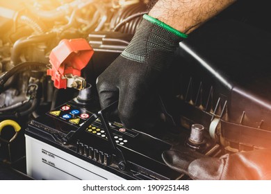 The Mechanic hand is pulling up an car old battery for replacement