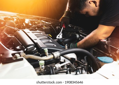 The Mechanic hand wearing black gloves is fasten the bolt with the socket wrench to repairing of the car engine