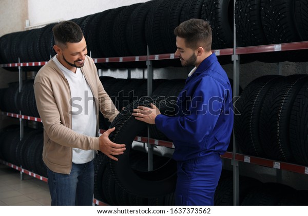Mechanic\
helping client to choose car tire in auto\
store