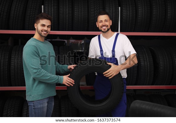 Mechanic\
helping client to choose car tire in auto\
store