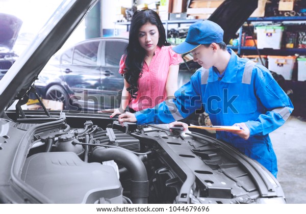 Mechanic\
helping a customer fixing a car in a repair\
shop