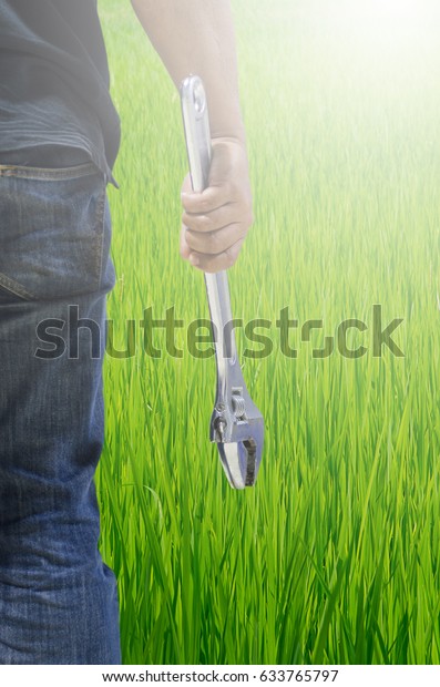 Mechanic\
holding the big wrench with a background\
pasture