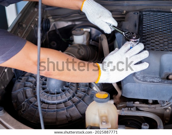 Mechanic holding a block wrench handle while fixing\
a car.