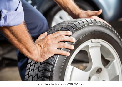 Mechanic Holding Car Tire At Garage