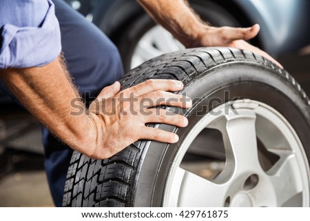 Mechanic Holding Car Tire At Garage