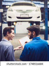 Mechanic Holding Clipboard With Car Owner In The Workshop Garage. Car Auto Services Concepts