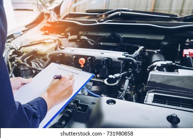 Mechanic Holding A Clipboard Of Service Order Working In Garage. Repair Service.