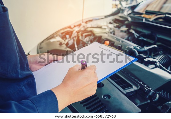 mechanic holding a clipboard of service order\
working in garage. Repair\
service.