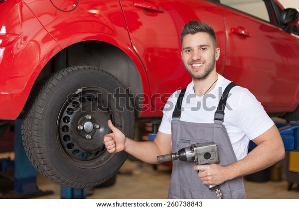 Mechanic\
holding an impact wrench and showing thumb\
up
