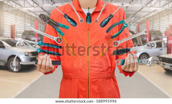 Mechanic holding many tools in car garage,\
Mechanic and tools\
concept.