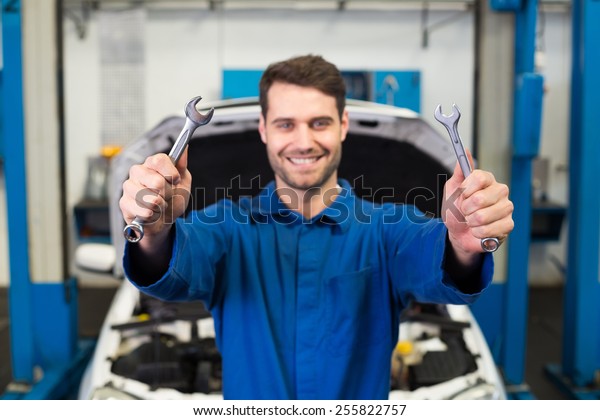 Mechanic\
holding pair of wrenches at the repair\
garage