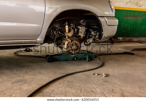 mechanic
holding pneumatic wrench by car at
garage