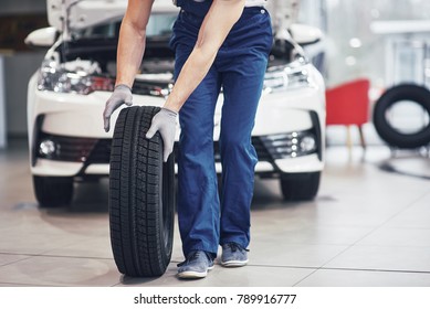 Mechanic holding a tire tire at the repair garage. replacement of winter and summer tires. - Shutterstock ID 789916777