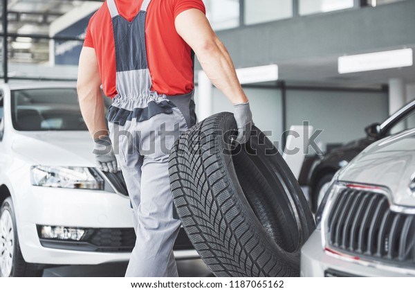 Mechanic holding a tire tire at the repair\
garage. replacement of winter and summer\
tires