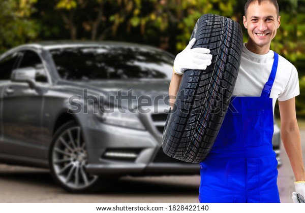 Mechanic holding a tire tire at the repair\
garage. replacement of winter and summer\
tires.