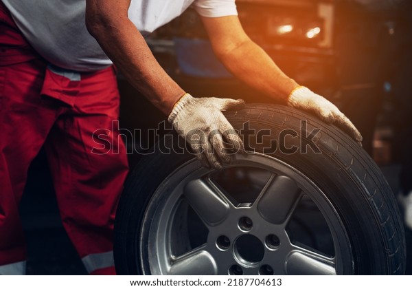 Mechanic holding a tire at the repair garage.\
Repair service.