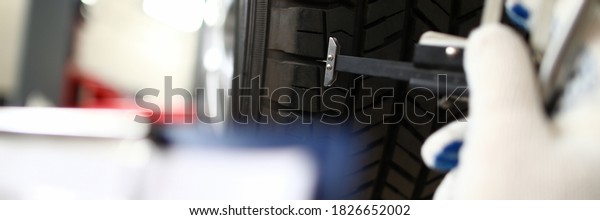 Mechanic holding tool hand that measures tire\
wear. Wheel balancing. Trust tire center to replace wheels.\
Pre-trial settlement damage after car accident. Tire fitting and\
balancing equipment