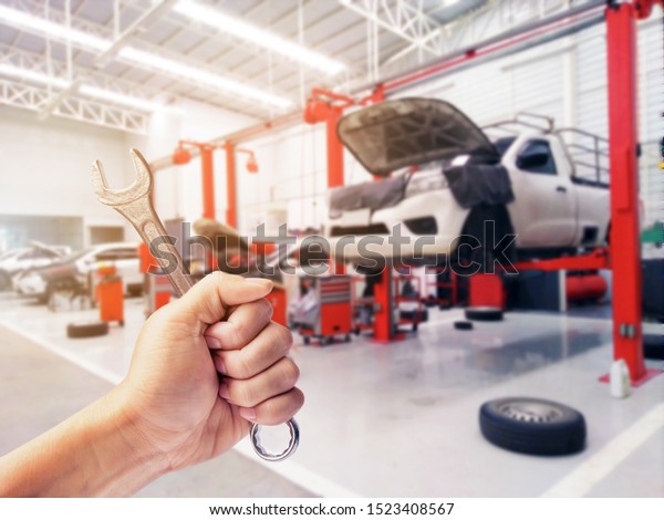 Mechanic holding a wrench at a car garage ,,Hand\
of technician auto mechanic with a wrench working in garage.\
service in auto repair\
station.