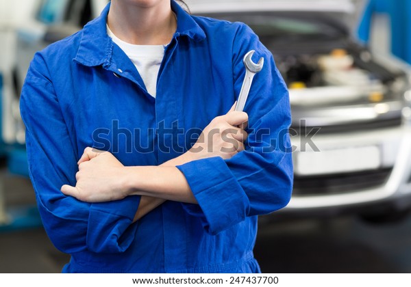 Mechanic holding wrench with crossed arms at the\
repair garage