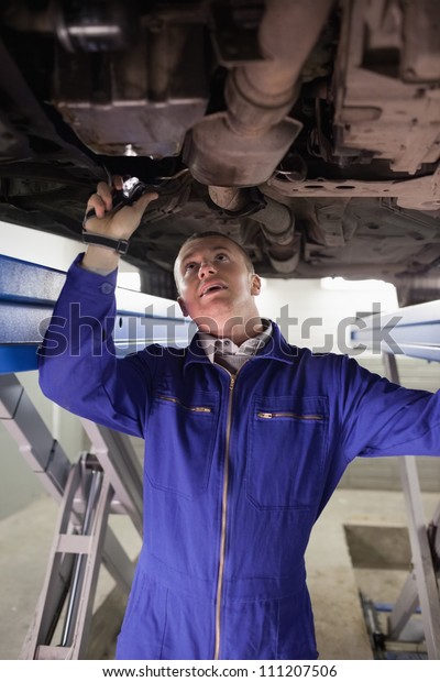 Mechanic\
illuminating a car with a flashlight in a\
garage