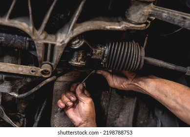 Un mecánico que inspeccione o repare la cremallera de la dirección bajo el vehículo en un taller de reparación automática.