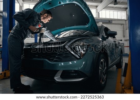 Mechanic inspecting technical condition of car engine