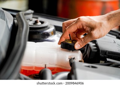 mechanic inspects the expansion tank with pink antifreeze. Vehicle coolant level in the car's radiator system. auto parts - Shutterstock ID 2009846906