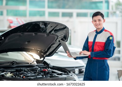 Mechanic inspects and repairs the car in the garage, the mechanic in the car repair shop stands next to the convertible. Use a computer system to check engine problems - car repair services