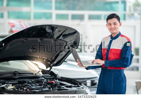 Mechanic\
inspects and repairs the car in the garage, the mechanic in the car\
repair shop stands next to the convertible. Use a computer system\
to check engine problems - car repair\
services