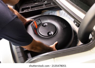 A Mechanic Is Installing A Car Donut-shaped Propane LPG Tank In A Spare Wheel Hole In A Auto Repair Garage