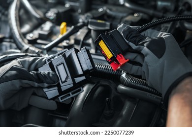mechanic installing chip tuning box on car engine