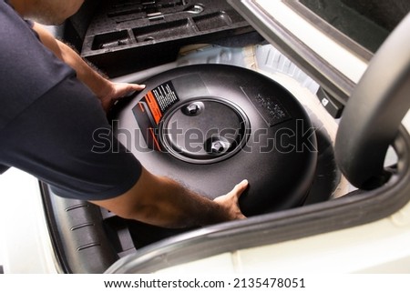 A mechanic is installing a propane or LPG container black circle shape of car LPG fuel system on trunk spare wheel holder, Alternative energy concept