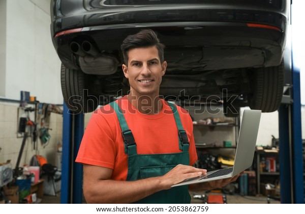 Mechanic with laptop for car diagnostic at\
automobile repair shop