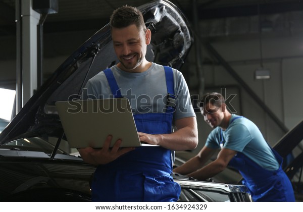 Mechanic with laptop doing car diagnostic at
automobile repair shop