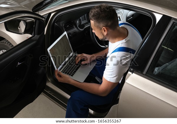 Mechanic with laptop doing car diagnostic at
automobile repair shop