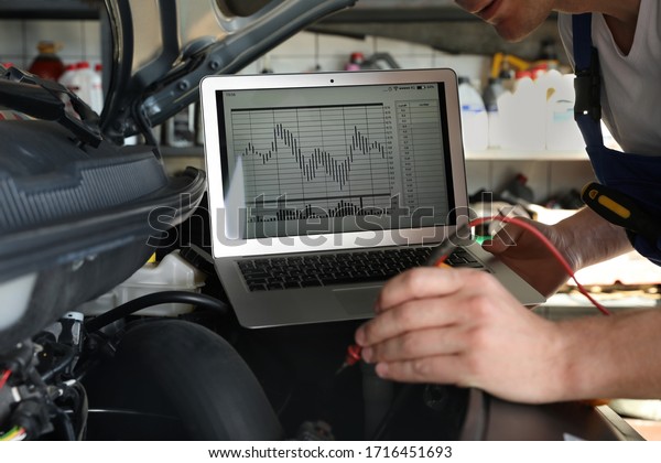 Mechanic with laptop doing car diagnostic at
automobile repair shop,
closeup