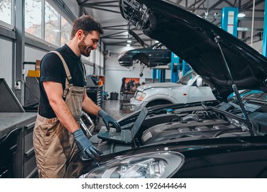 Mechanic With Laptop Near Car Engine. Modern Car Diagnostic Program. Car Service Concept. Side View.