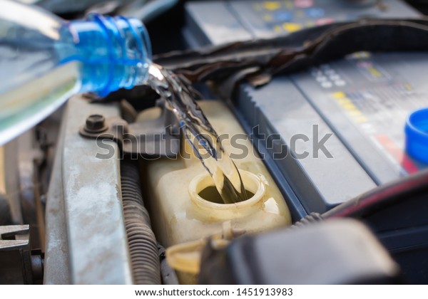 Mechanic maintenance small business service, Man\
pouring water for radiator on car.\
